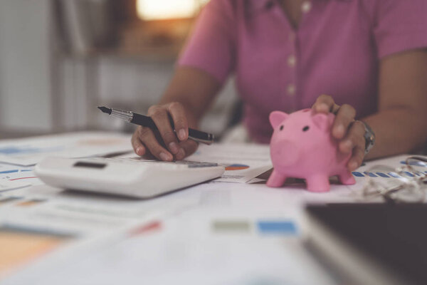 Asian Businesswoman calculating saving account balance with calculator, account and saving concept.