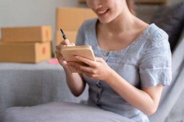 Asyalı küçük işletme sahibi ev ofisinde çalışıyor. Ticari perakende pazarı ve çevrimiçi pazarlama dağıtımı, KOBİ e-ticaret kavramı.