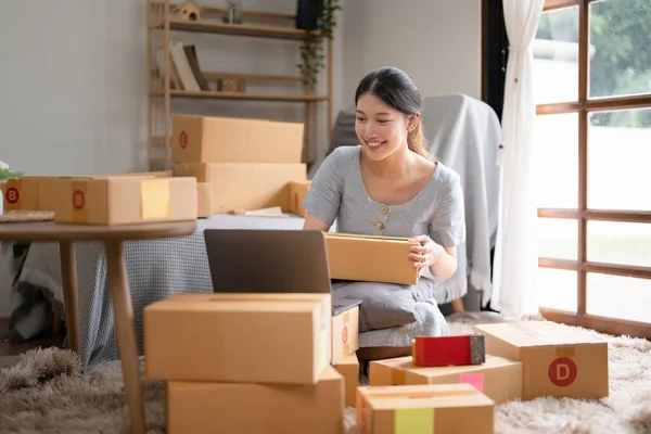 Asyalı küçük işletme sahibi ev ofisinde çalışıyor. Ticari perakende pazarı ve çevrimiçi pazarlama dağıtımı, KOBİ e-ticaret kavramı.