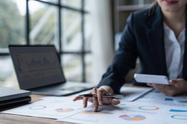 Asyalı İş kadını elinde kalemle sosyal ağ diyagramı ile finansal evraklara işaret ediyor..