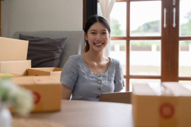 Asyalı küçük işletme sahibi ev ofisinde çalışıyor. Ticari perakende pazarı ve çevrimiçi pazarlama dağıtımı, KOBİ e-ticaret kavramı.