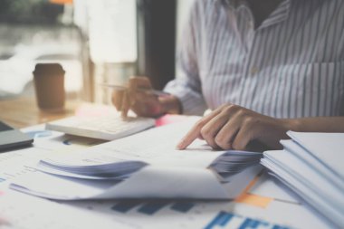 İş kadını, ofis, vergi, muhasebe, istatistik ve analitik araştırma konseptindeki ahşap masa üzerinde mali denetim bütçesi için hesap makinesi kullanıyor..