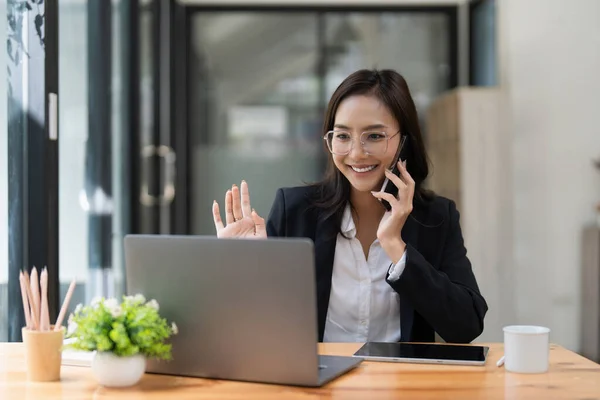 Asyalı Kadını Müşterisiyle Cep Telefonuyla Konuşuyor Dizüstü Bilgisayarla Çalışıyor — Stok fotoğraf