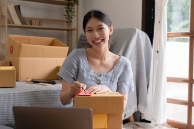 Asyalı küçük işletme sahibi ev ofisinde çalışıyor. Ticari perakende pazarı ve çevrimiçi pazarlama dağıtımı, KOBİ e-ticaret kavramı.