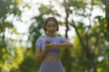 Spor giyimli çekici bir Asyalı kadın parkta yoga yapıyor..