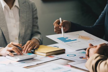 Bir grup Asyalı iş adamı toplantı odasındaki mali grafiği analiz ediyor..