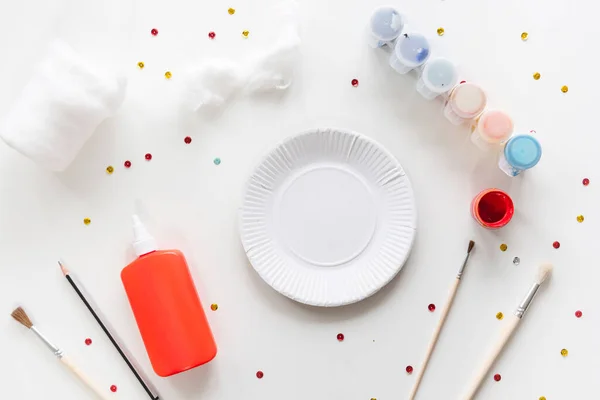 Çocuk, Noel Baba 'nın kağıt tabaktan yaptığı parçaları yapıştırıyor. El yapımı. Çocukların yaratıcılığı projesi, el işleri, çocuklar için el sanatları. DIY. Adım adım.