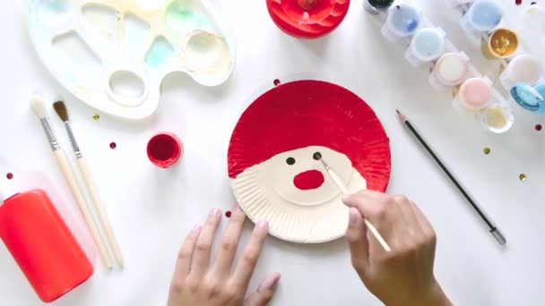 The child glues the parts Santa made from paper plate. Handmade. Project of childrens creativity, handicrafts, crafts for kids. — Stock Video