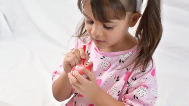 Happy little girl with bunny ears painting the egg with fiberpen, preparing for Happy Easter day. — Stock Video