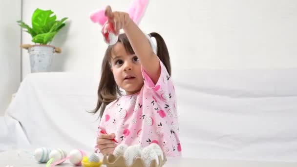 Niña feliz con orejas de conejo pintando el huevo con fibra, preparándose para el feliz día de Pascua. — Vídeo de stock