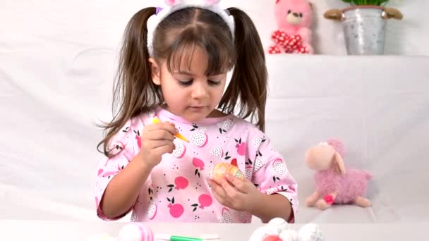 Happy little girl with bunny ears painting the egg with fiberpen, preparing for Happy Easter day. Preparing handmade — Stock Video