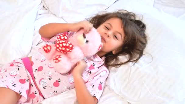 Schattig donker haar dat 's morgens zoet op beddengoed met teddybeer ligt. Kinderdromen, comfort, rust en vrede. — Stockvideo