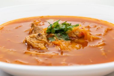 Beyaz tabakta kırmızı borş çorbası.