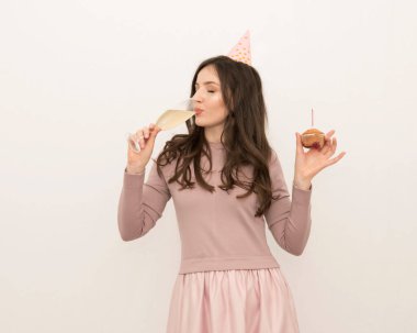 Genç ve güzel bir kadın bayramı şampanya ve pembe elbiseli bir pastayla kutluyor.