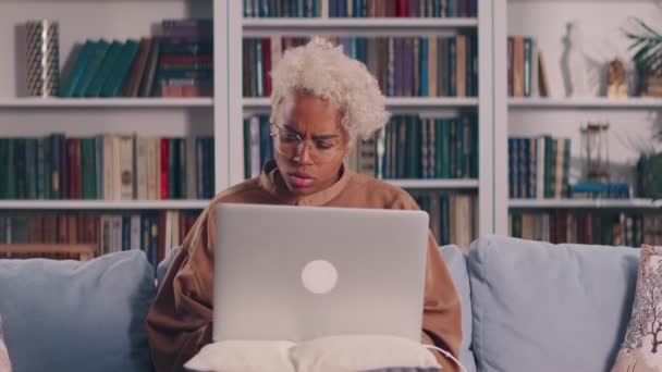 Африканська жінка, яка користується ноутбуком вдома, боїться поганої роботи з електронним пристроєм. — стокове відео