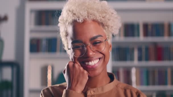 African American millennial kobieta uśmiech patrzeć na aparat stoją w pomieszczeniach sam — Wideo stockowe