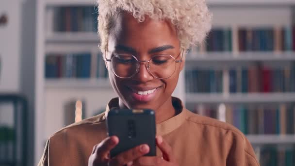 Sonriente mujer afroamericana joven disfrutando el uso de aplicaciones de software móvil — Vídeo de stock