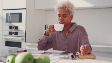 Afro-Amerikan bir kadının portresi. Mutfakta çay içiyor.