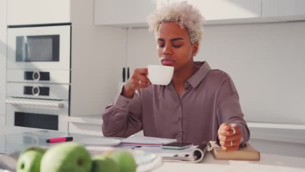 Retrato da jovem mulher afro-americana satisfeita bebendo chá na cozinha — Vídeo de Stock