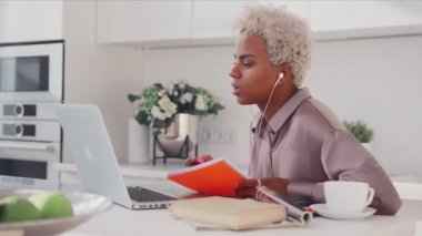 Odaklanmış genç kadın video çağrısı yapıyor. Özel ders yazıyor, uzaktan eğitim alıyor.