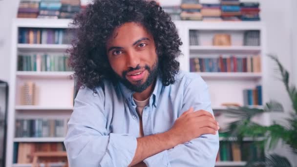 Hombre guapo de Oriente Medio sonriendo encantadoramente sentado en el escritorio en la sala de estar — Vídeo de stock