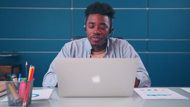 Афроамериканец носит наушники видео вызова на ноутбук — стоковое видео
