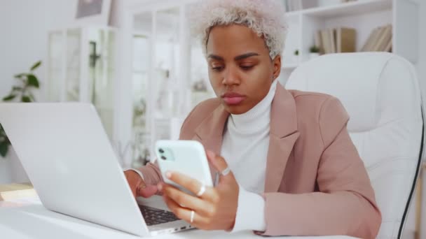 Az etnikai nő mobilalkalmazással szinkronizálja az adatokat a számítógéppel Bluetooth-on keresztül. — Stock videók