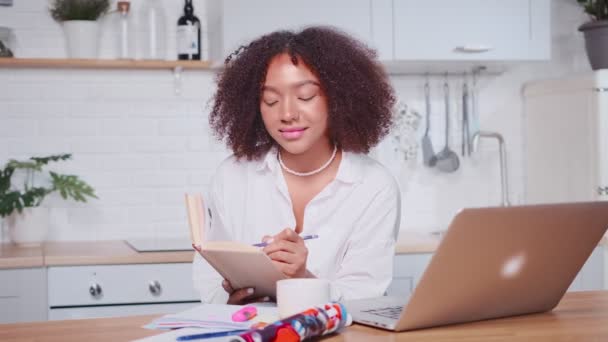 Succesvolle Afro-Amerikaanse vrouw neemt notities in werkmap op zoek naar laptop — Stockvideo