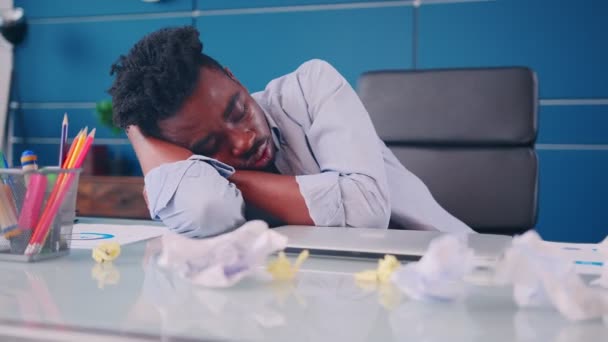 Tired young African American man office worker sleeps at work desk. — Stock Video