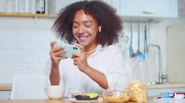 Neşeli genç Afrikalı Amerikalı kadın telefonda oyun oynuyor..