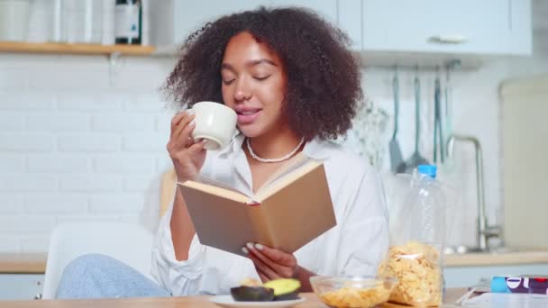 매력적으로 웃는 아프리카 계 미국인 여성 이 무엇인가를읽고 차를 마시는 모습. — 비디오