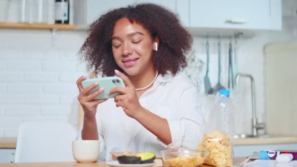 Afro-Amerikaanse vrouw houdt smartphone horizontaal speelt games online — Stockvideo