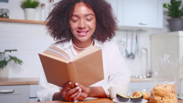 Attraktive Afroamerikanerin blättert durch Buchseiten und lächelt. — Stockvideo
