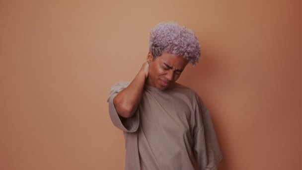 Africano mulher caretas de dor intensa massagens pescoço para revelar tensão muscular — Vídeo de Stock