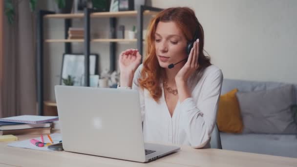 Éxito mujer caucásica en auriculares con micrófono conversaciones y gestos con las manos. — Vídeos de Stock