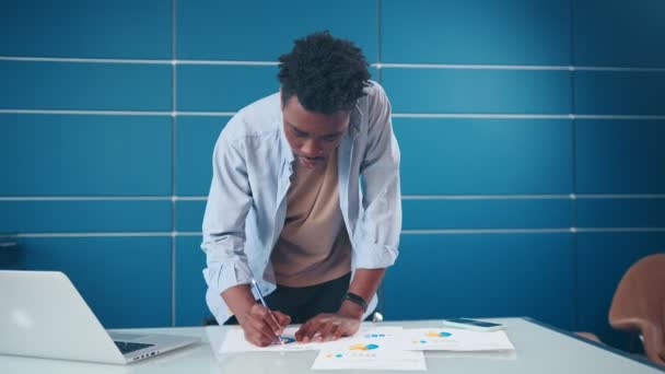 African American man står på kontoret skrivbord med anteckningar planering agenda — Stockvideo