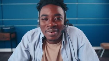 Web kamerasıyla konuşan kulaklıklı mutlu Afrikalı Amerikalı adam merhaba diyor..