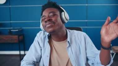 Genç Afrikalı Amerikalı adam kablosuz kulaklık takıyor. Eğlenceli müzik dinliyor.