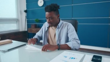 Mutlu genç Afrikalı Amerikalı adam ara verirken kağıt uçak fırlatıyor.