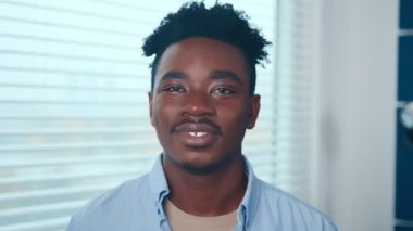 Gülümseyen genç Afrikalı Amerikalı adam ana ofiste kameraya bakıyor..