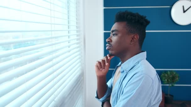 Νεαρός στοχαστικός Αφροαμερικανός επιχειρηματίας κοιτάζει έξω από το παράθυρο. — Αρχείο Βίντεο