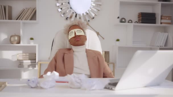 Tired African American businesswoman with memo notes on eyes napping in office — Stock Video