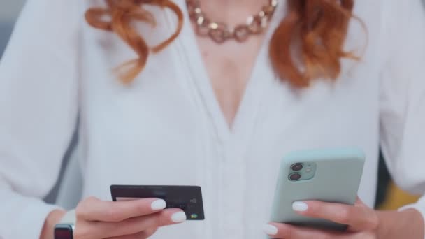 Tevreden blanke vrouw voert credit card gegevens in de telefoon en glimlacht. — Stockvideo