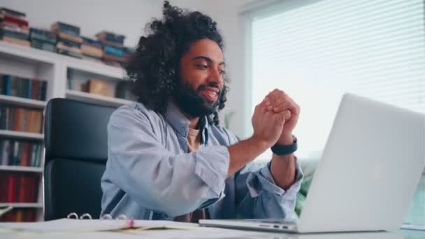 Entusiasta joven árabe sonriendo hablando sobre auriculares mirando en el ordenador portátil — Vídeos de Stock