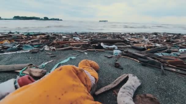 Zanieczyszczona plaża z zabawką leżącą wśród śmieci nadmiaru śmieci w wodach — Wideo stockowe