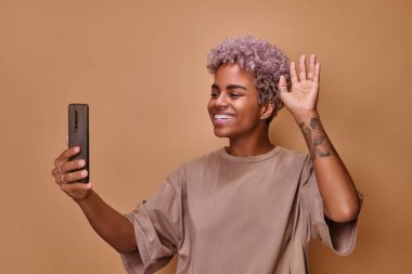 Genç mutlu Afrikalı Amerikalı kadın telefona bakıyor ve video blogları yazıyor.