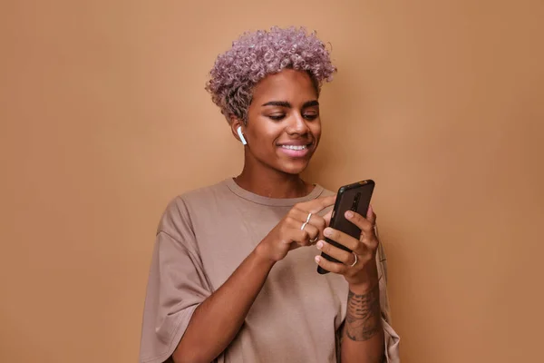 Muziekliefhebber Afro-Amerikaanse vrouw met draadloze hoofdtelefoon en mobiele telefoon — Stockfoto