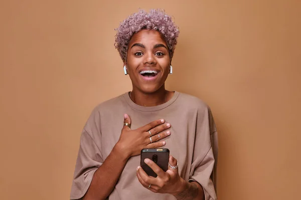 Nadšení mladá Afroameričanka s bezdrátovými sluchátky a telefonem — Stock fotografie