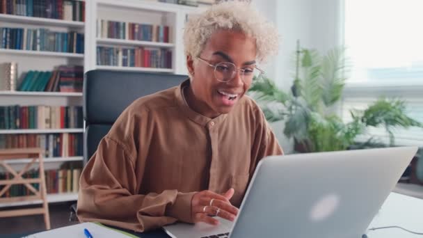Genç Afrikalı Amerikalı kadın, dizüstü bilgisayarında gördüklerine seviniyor. — Stok video