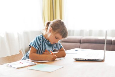 Çocuk bir dizüstü bilgisayar kullanıyor ve evdeki video öğretmeniyle internetten ders çalışıyor. Evde eğitim, uzak öğrenim